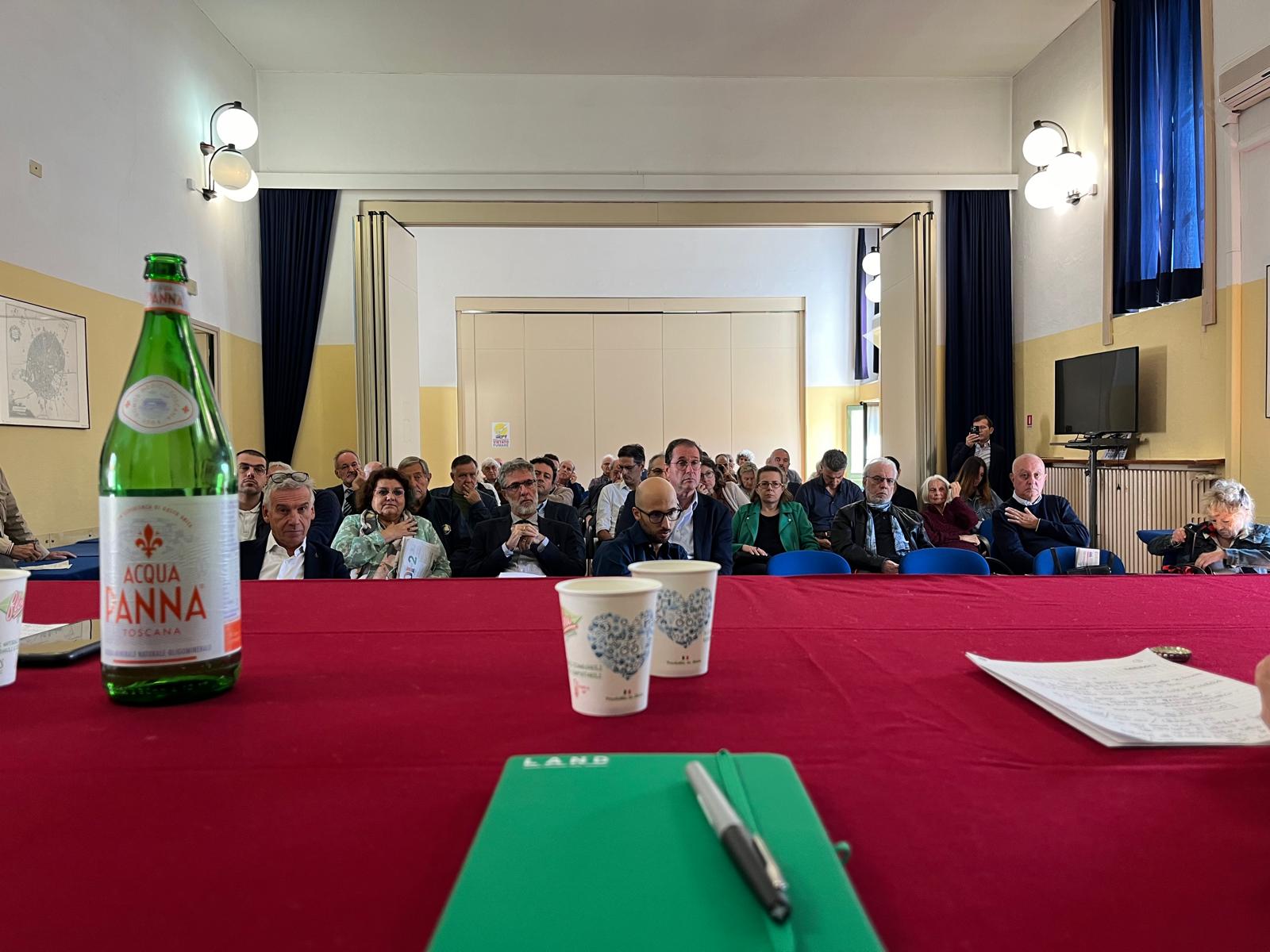 Red tablecloth with notebook branded LAND and a room with people on chairs