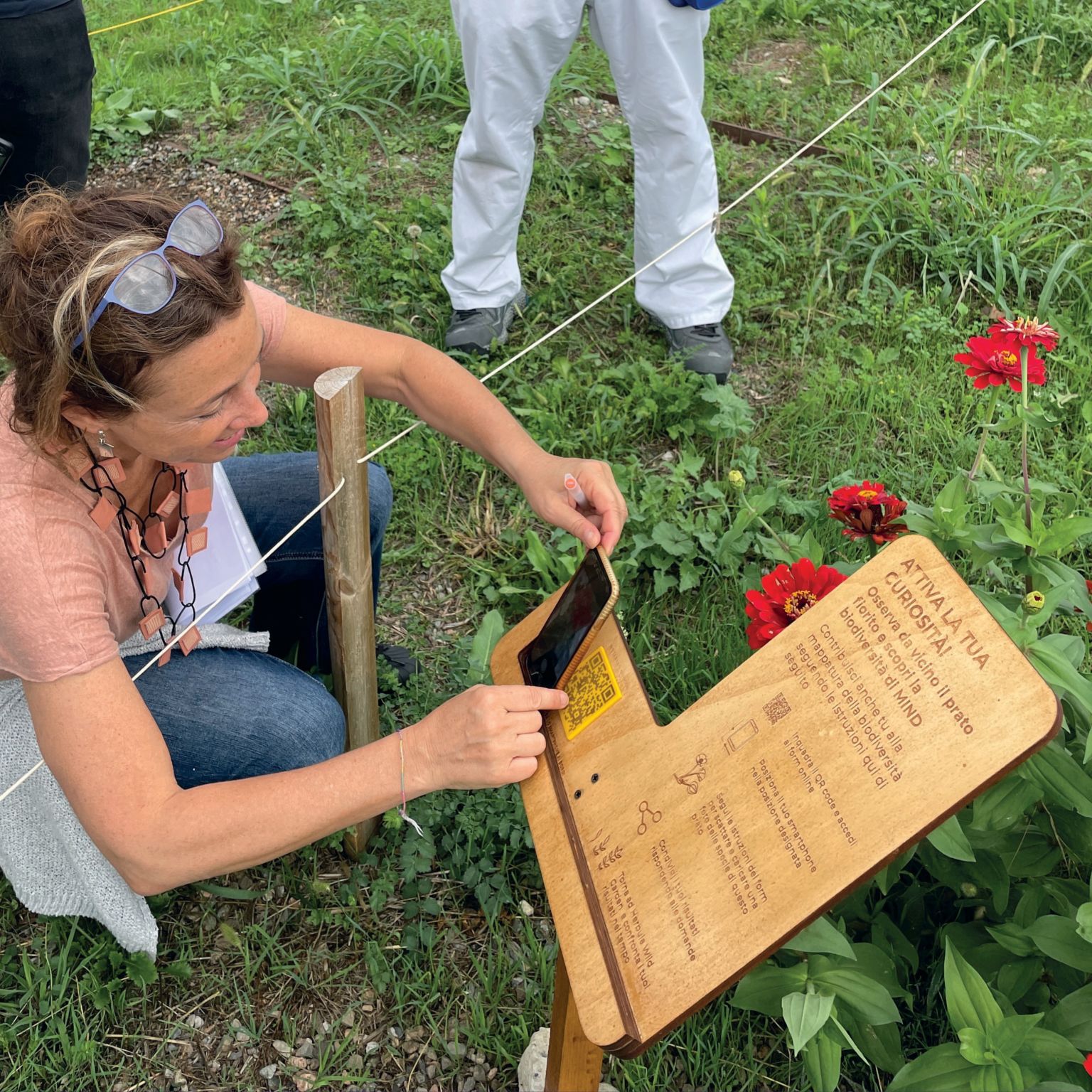 a woman scans a qr-code from a wooden signpost