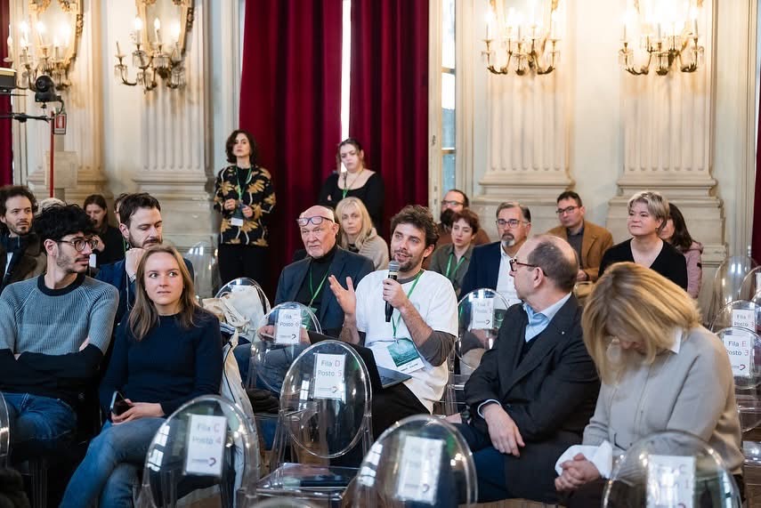 A man speaking at the microphone in an audience